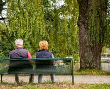 Älteres Paar auf einer Bank im Park an einem See, Aufnahme von