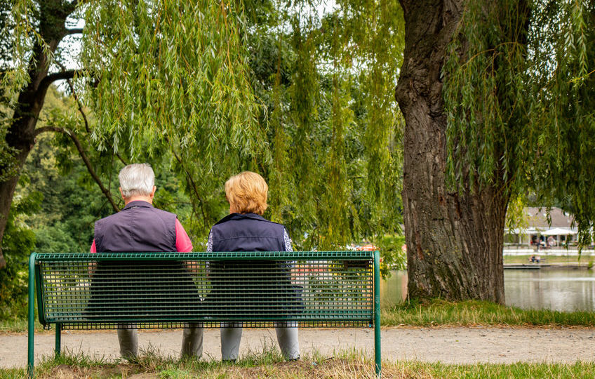 Älteres Paar auf einer Bank im Park an einem See, Aufnahme von